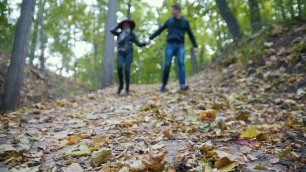 Pareja joven en el parque de otoño - divertirse y correr entre hojas amarillas, cámara lenta — Vídeo de stock