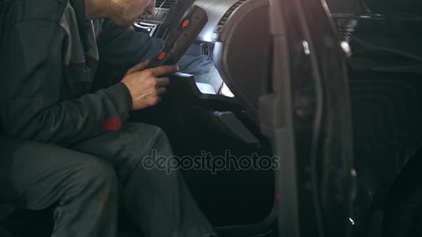 Mecánico con la lámpara está comprobando dentro del coche en el servicio de automóvil garaje, de cerca — Vídeos de Stock