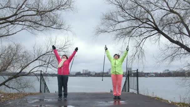 Oudere vrouwen in herfst park doen warm up voor nordic-walking — Stockvideo