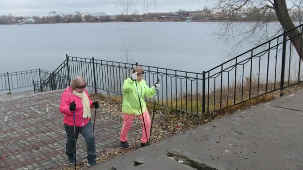 Nordic walking para mujeres mayores al aire libre - dos señoras mayores tienen entrenamiento al aire libre — Vídeos de Stock