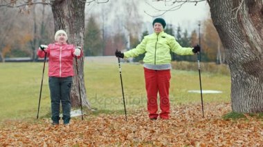 Sonbahar Park sıcak önce egzersizleri - Kuzey yürüyüşü yapıyor iki mutlu yaşlı kadın
