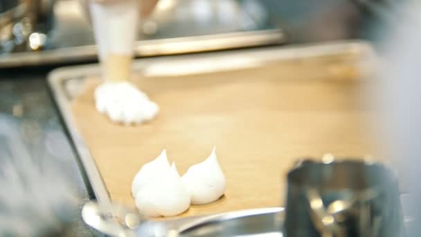 Σεφ μαγειρικής μαρέγκα στην κουζίνα - ζαχαροπλαστικής σωλήνα εξαπλωθεί μαρέγκα σε ένα φύλλο ψησίματος - Pavlova επιδόρπιο — Αρχείο Βίντεο