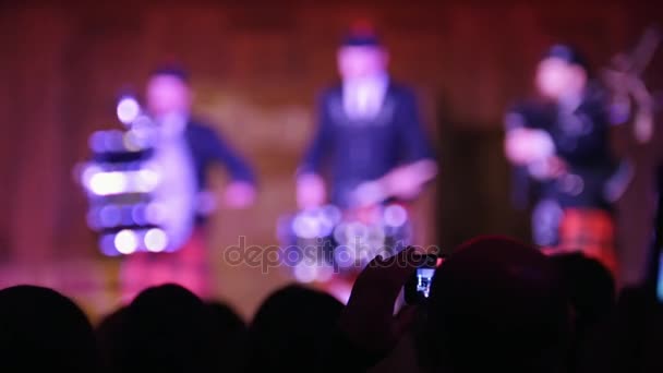 Зрители на концерте - люди снимают выступление на смартфоне, шотландские музыканты — стоковое видео