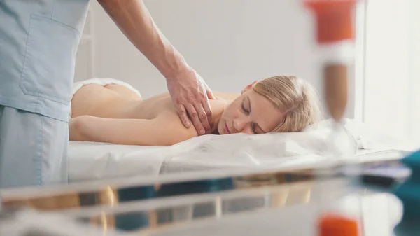 Mężczyzna fizjoterapeuta masaż kobiety z powrotem w gabinecie lekarskim — Zdjęcie stockowe