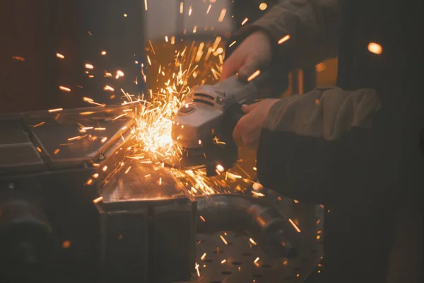 Bright sparks - metal workshop - worker grinding metal construction with a circular saw, close up