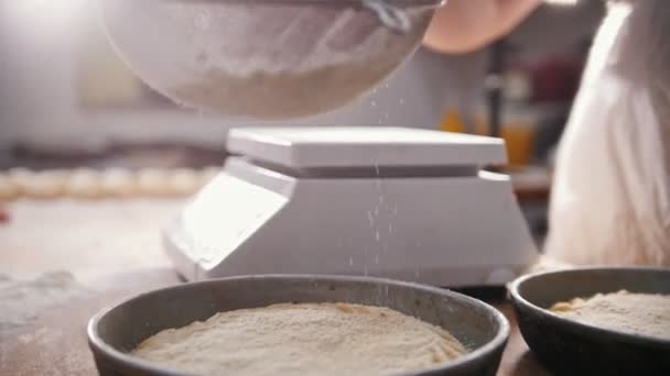 Cook sifts mouky zdobení pečiva v pekárně — Stock video