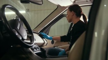 Genç esmer kadın eldiven fırça ile bir araba iç yıkıyor