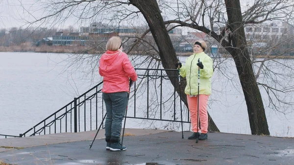 Two elderly grandma women doing exercises for neck outdoor