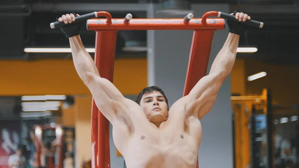 Young athlete man pulling up in a gym, close up — Stock Photo, Image