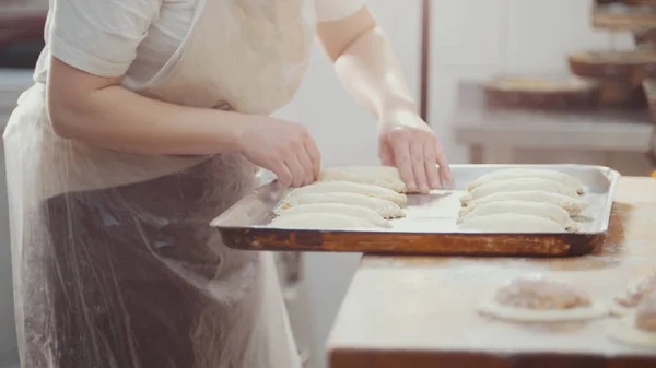 Повар кладет пироги на поднос для выпечки — стоковое фото