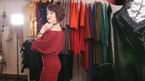 Hermosa mujer en vestido de noche rojo posando para el fotógrafo en la sala de exposición boutique — Vídeo de stock