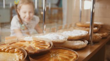 Penceredeki seçerek, de-odaklı pastaları kız bir helezon ile bakar