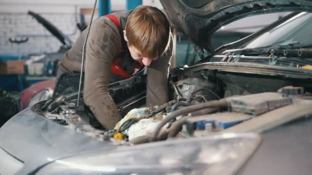 Monteur controleert en reparaties van de motor van de auto, auto reparatie, werken in de werkplaats, revisie, onder de motorkap — Stockvideo