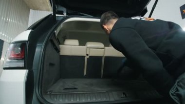 Genç adam araba iç vakum temizleyici, bagajında temizlik temizler