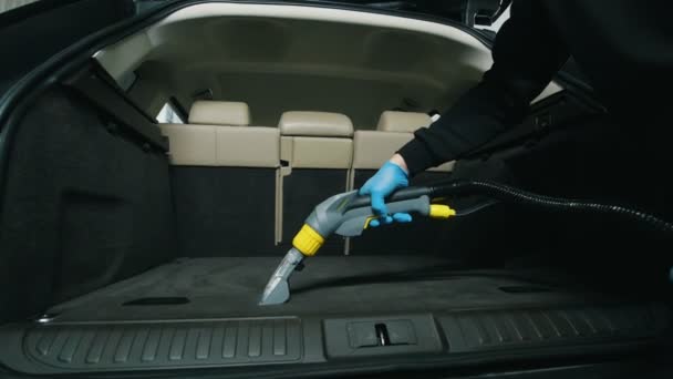 Вологе прибирання багажника, людина очищає інтер'єр автомобіля пилососом — стокове відео