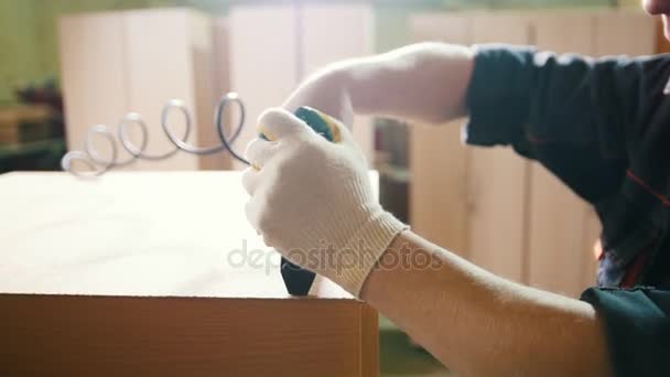 Carpinteiro trabalhando com um grampeador industrial elétrico na fábrica, fixando detalhes da mobília, close-up — Vídeo de Stock