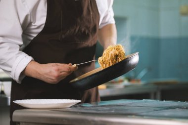 Şef spagetti tabağına sunmaktadır.