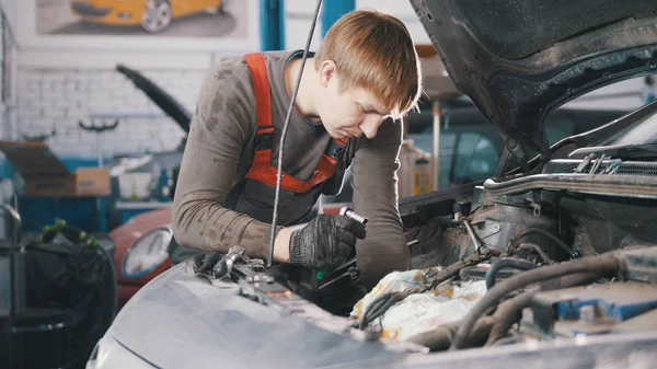 Monteur controleert en reparaties van de motor van de auto, auto reparatie, werken in de werkplaats, revisie, onder de motorkap — Stockfoto