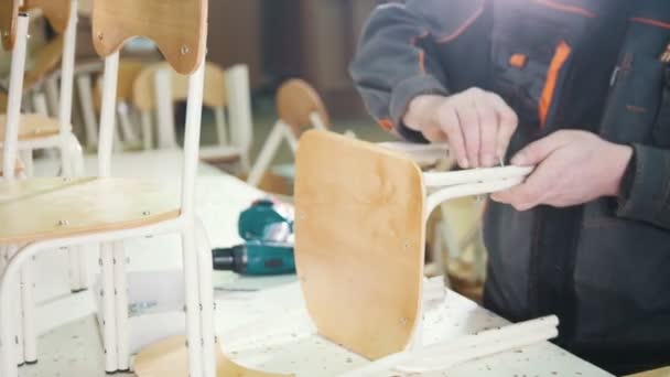 Werknemer timmerman is schroeven stoel been bij een meubelfabriek — Stockvideo