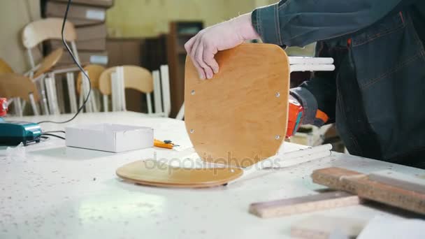 Trabajador carpintero hombre está atornillando pata de la silla en una fábrica de muebles — Vídeos de Stock