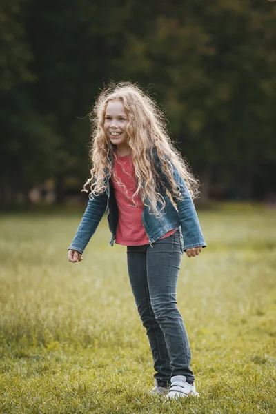 公園でジーンズのジャケットを着て笑顔のかなり金髪の子 — ストック写真