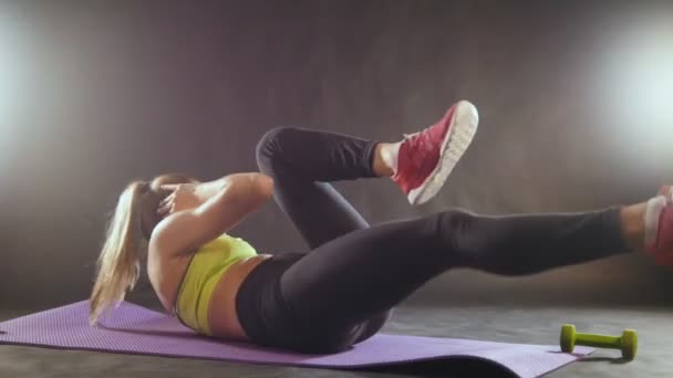 Attraktive junge Frau im Sportanzug im Fitnessstudio macht Übungen für den Bauch — Stockvideo