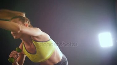 Genç fitness kadının ellerinde - dumbbells ile eğitim Studio çekici modeli yapması