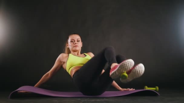 Молодая спортсменка, занимающаяся спортом с гантелями в ногах - привлекательная модель фитнеса в студии — стоковое видео