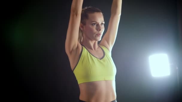 Молодая блондинка, занимающаяся тренировками с гантелями в руках - привлекательная модель фитнеса в студии — стоковое видео