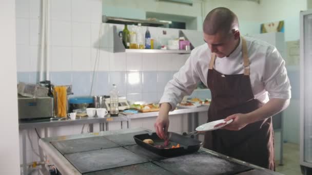 junger männlicher Chefkoch in Uniform bereitet ein Fleisch zu