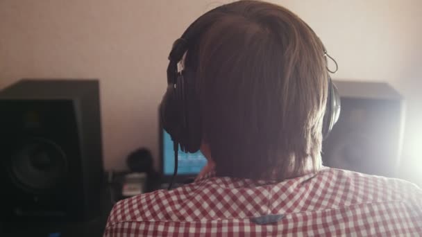 Compositor joven compone música en el ordenador, ingeniero de sonido trabajando — Vídeo de stock