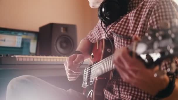 Νεαρός μουσικός συνθέτει και ηχογραφεί μουσική να παίζει την κιθάρα που χρησιμοποιούν υπολογιστή και πληκτρολόγιο — Αρχείο Βίντεο