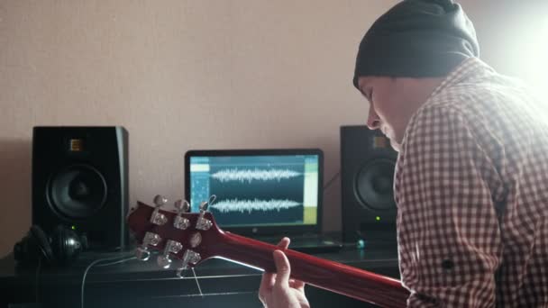 Unga trendiga manliga musiker komponerar och spelar soundtracket spela gitarr med hjälp av dator — Stockvideo