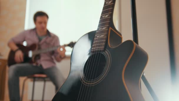 Jonge aantrekkelijke musicus componeert muziek op de gitaar en speelt, andere muziekinstrument op de voorgrond wazig concept — Stockvideo