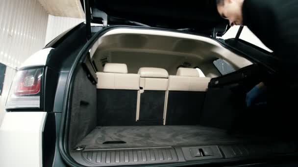 Samochód do czyszczenia - człowiek czyści szafa pnia luksusowych pojazdów z odkurzacza — Wideo stockowe