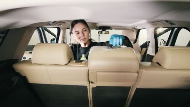 Fahrzeugreinigung - kaukasische junge Frau wäscht Sessel eines Luxusautos mit Bürste — Stockvideo