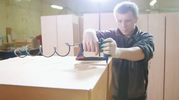 Carpenter working with an electric industrial stapler on the factory, fixing furniture details, close-up — Stock Photo, Image