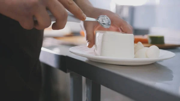 Шеф режет сыр на коммерческой кухне. — стоковое фото