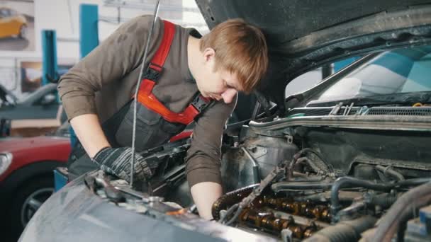 Der Mechaniker arbeitet unter der Motorhaube des Autos — Stockvideo