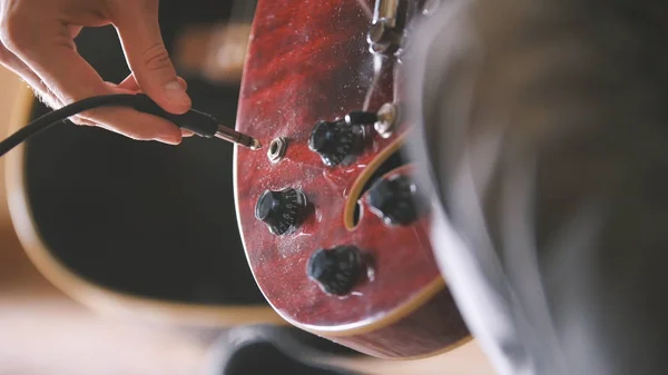 Músico enchufa y sintoniza su guitarra antes de una actuación, las manos se cierran —  Fotos de Stock