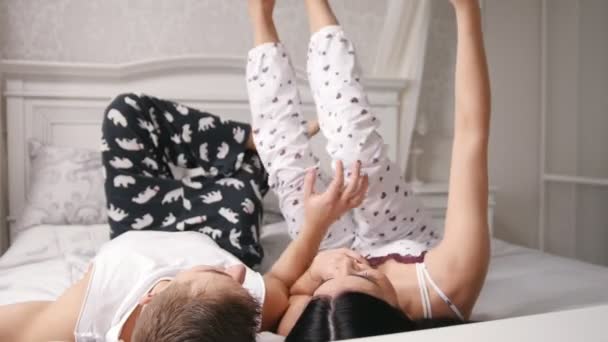 Boldog vidám szerető pár selfie így az ágy, a fiatal, vonzó srác és a lány pizsama fekve — Stock videók