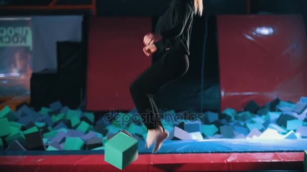 Young sportive woman acrobats perform acrobatic tricks - jumping in a trampoline hall, slow-motion — Stock Video