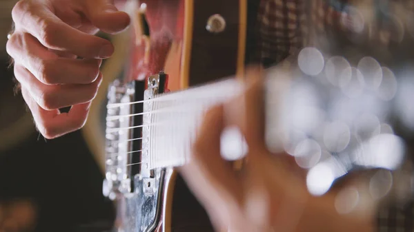 Чоловік музикант грає на гітарі, руки крупним планом, фокусується на гітарній дошці — стокове фото