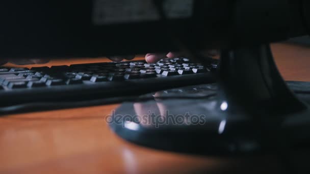 Пальцы мужчины печатают на клавиатуре компьютера рядом с персональным компьютером — стоковое видео