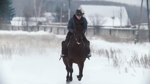 Mulher jovem galopando no exterior nevado no cavalo vermelho - perca o chapéu, câmera lenta — Vídeo de Stock
