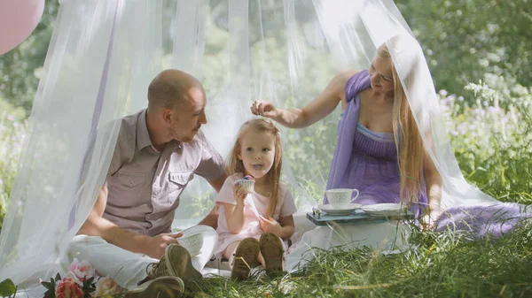 Счастливая семья, весело проводящая время на свежем воздухе в зеленом парке - мать, отец и дочь — стоковое фото