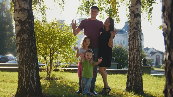 Retrato de la familia en el parque de verano - agitando las manos en la cámara —  Fotos de Stock