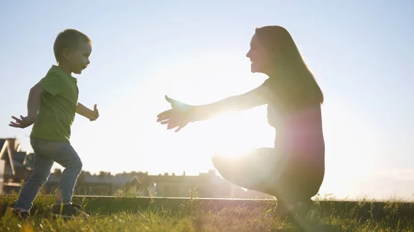 Moeder speelt met zoon in zomer zonsondergang park - kind loopt naar mama — Stockfoto