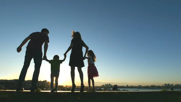 Familie bij zonsondergang - vader, moeder, dochter en zoontje samen - silhouet — Stockfoto