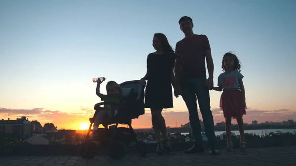 Familie bij zonsondergang - vader, moeder, dochter en zoontje - silhouet — Stockfoto
